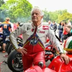 Giacomo Agostini, leyenda del motociclismo, con su casco y mono de competición.